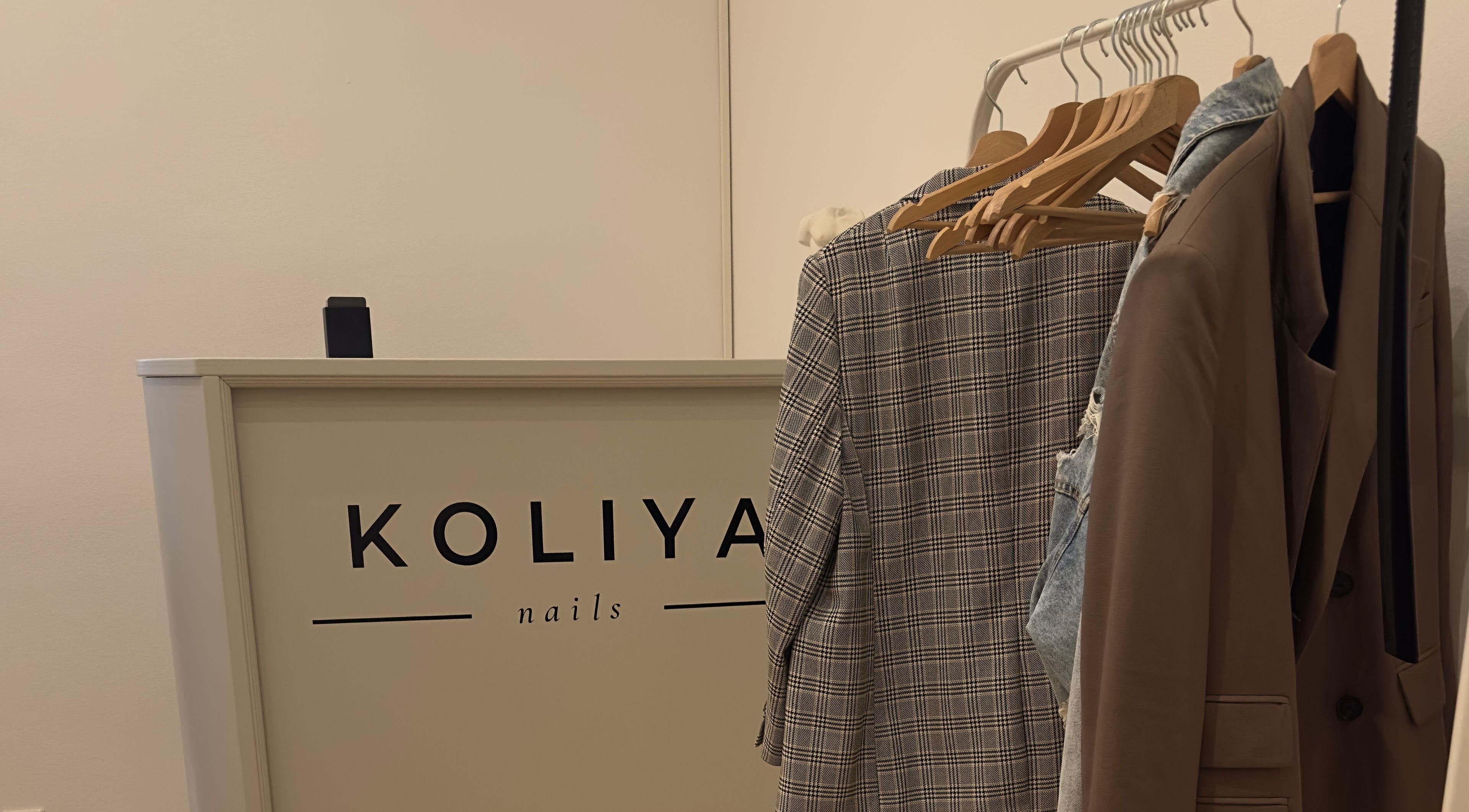 Entrance display at Koliya Nails, Wien with elegant coat racks and reception desk.