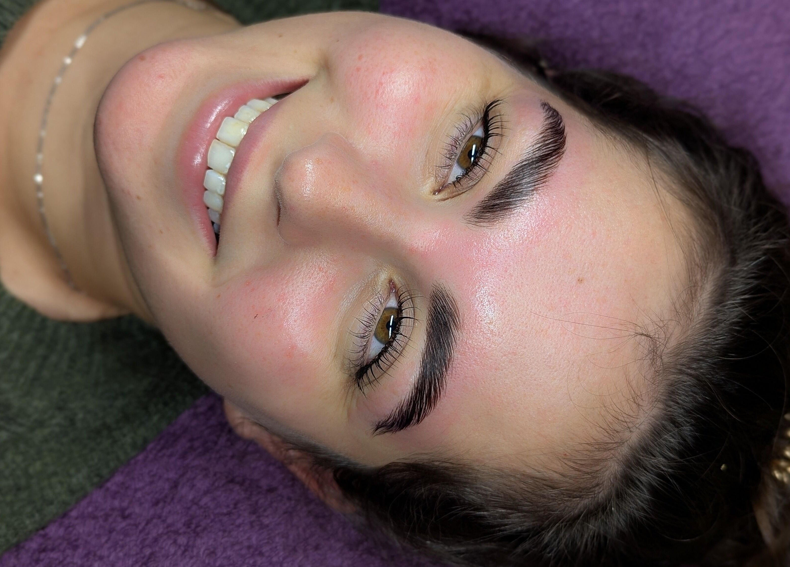 Smiling woman with perfect brows at Affinity Beauty Windsor, Windsor, England, GB on purple pillow.