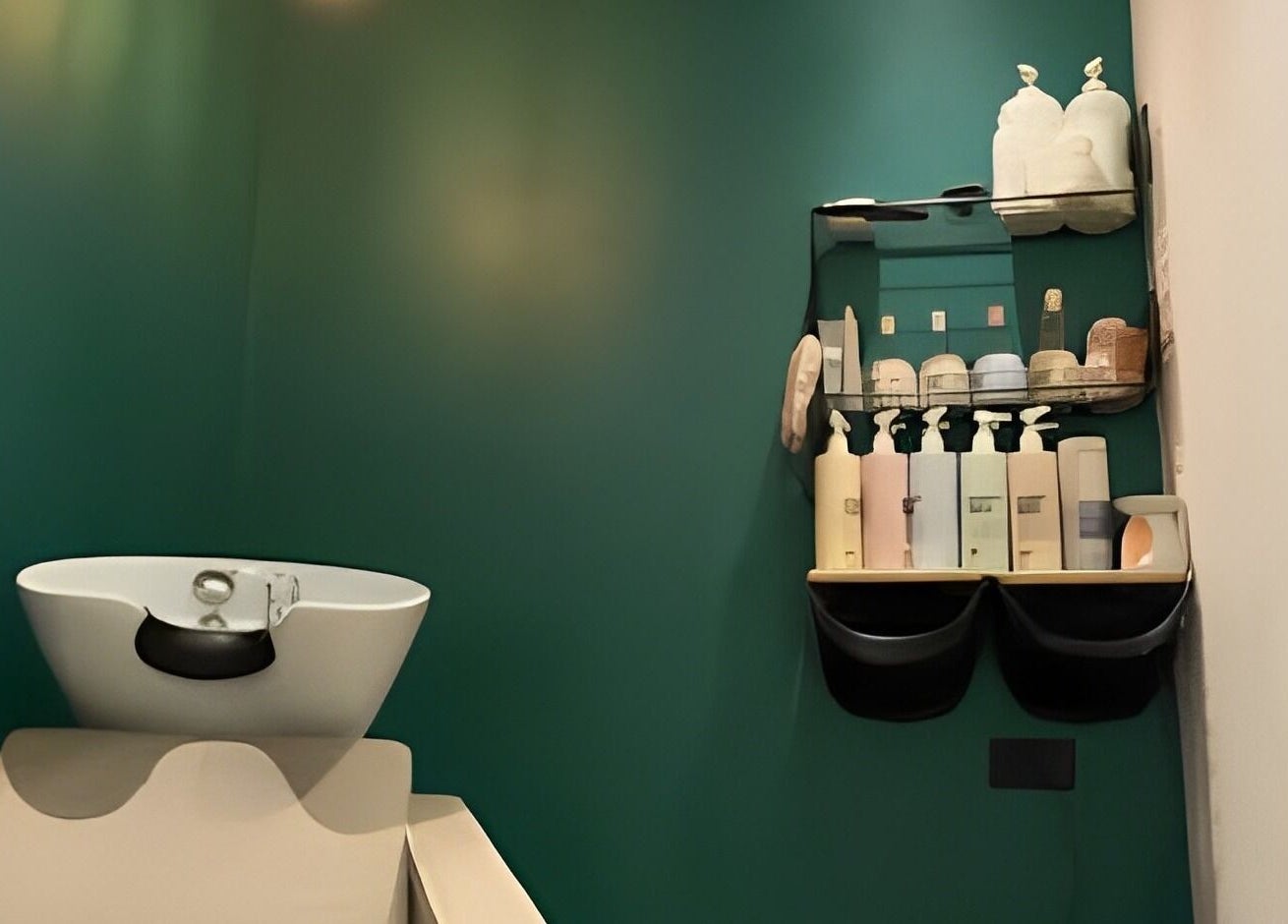 Create Salon's wash station in Cardiff, Wales, GB, with sleek green walls and beauty products displayed.