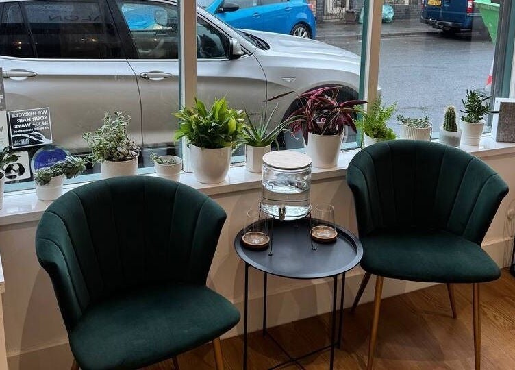 Inviting green chairs and plants at Create Salon, Cardiff, Wales, GB, offer a relaxing waiting area.
