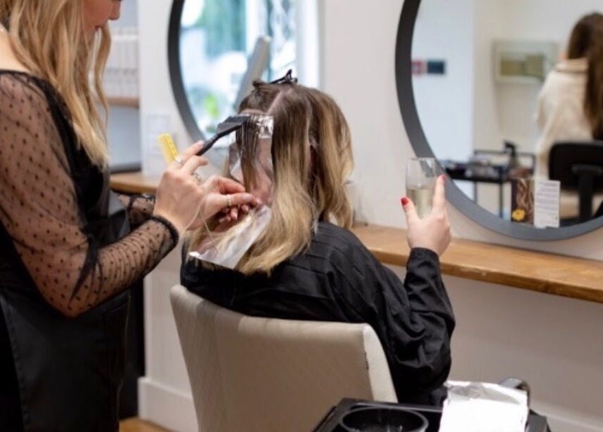 Client enjoying hair treatment at Create Salon, Cardiff, Wales, GB with stylist applying color.