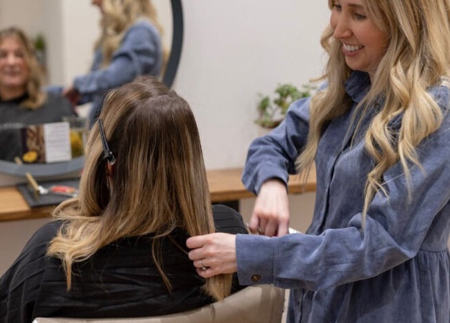 Stylist at Create Salon in Cardiff, Wales, GB, attentively working on a client's hair in a cozy setting.