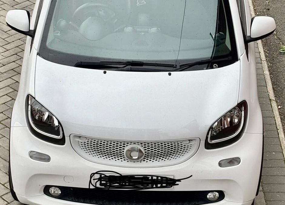 White car parked outside Funky Feet in Weymouth, England, GB, highlighting urban charm.