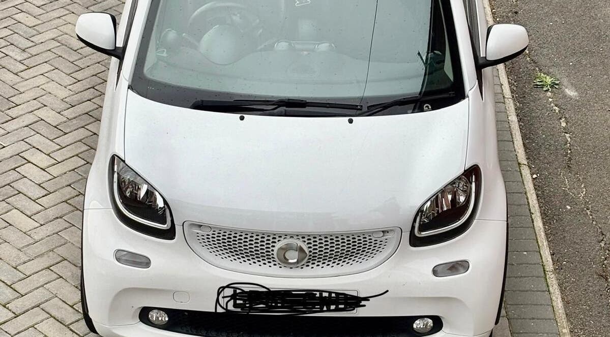 White car parked outside Funky Feet in Weymouth, England, GB, highlighting urban charm.