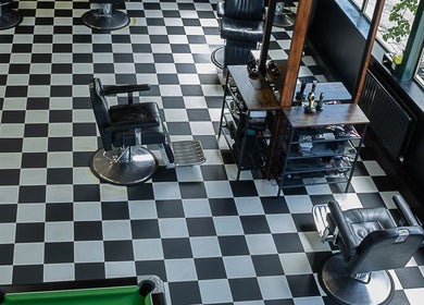 Interior of Skinny Isaac's Barber Shop & Hair System Studio in Belfast, showcasing stylish checkered floor and chairs.