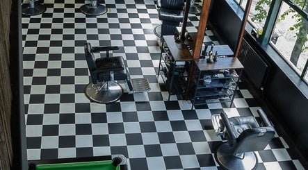 Interior of Skinny Isaac's Barber Shop & Hair System Studio in Belfast, showcasing stylish checkered floor and chairs.