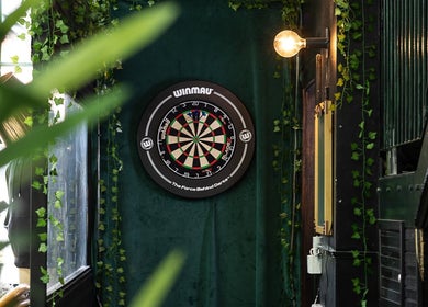 Dartboard on lush green wall at Skinny Isaac's Barber Shop & Hair System Studio, Belfast, Northern Ireland, GB.