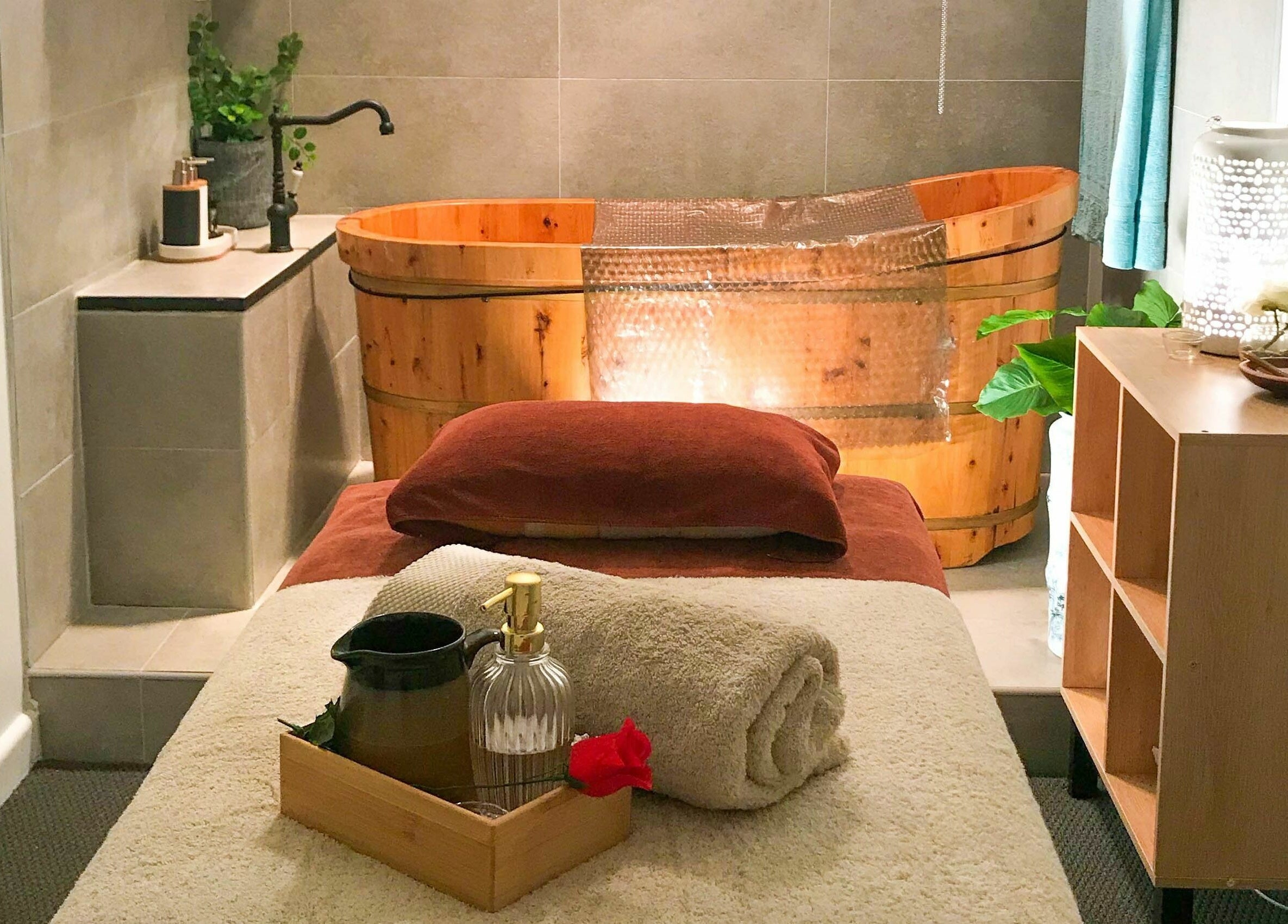 Relaxing spa room at Kamiya Day Spa, Ashburton, Victoria, AU with massage bed and wooden tub for ultimate tranquility.
