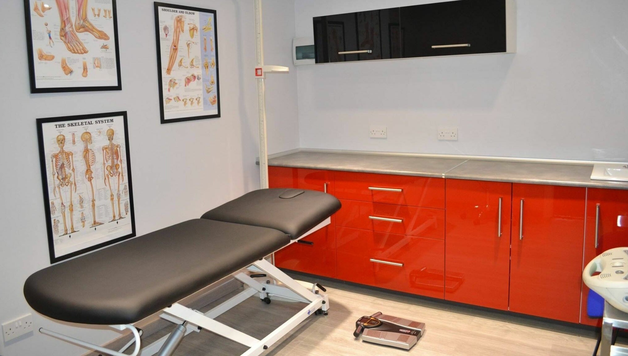 Modern treatment room at Activ Sports Medicine and Performance Clinic, Gibraltar, GI with sleek red cabinets.