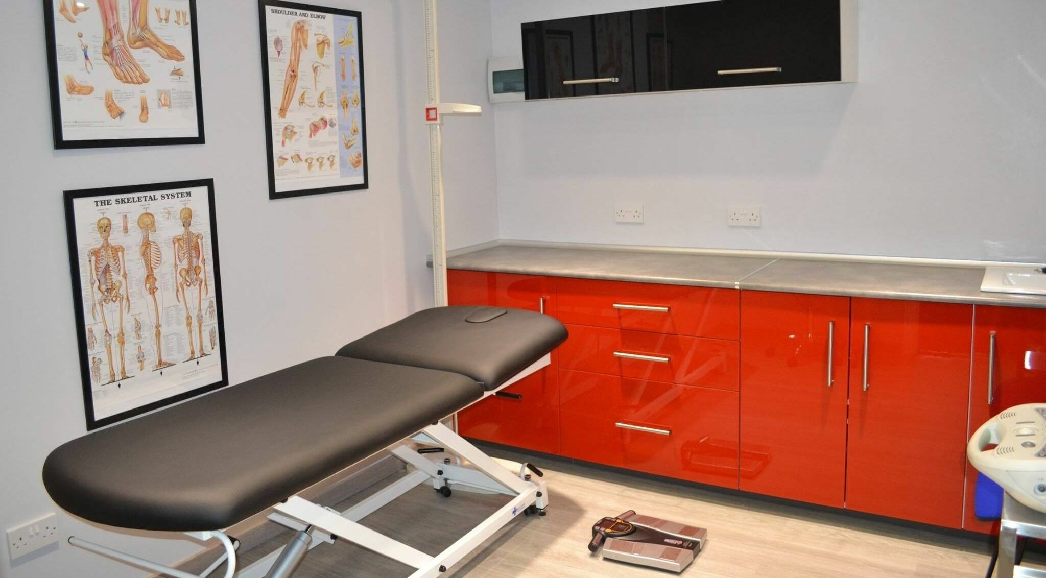 Modern treatment room at Activ Sports Medicine and Performance Clinic, Gibraltar, GI with sleek red cabinets.