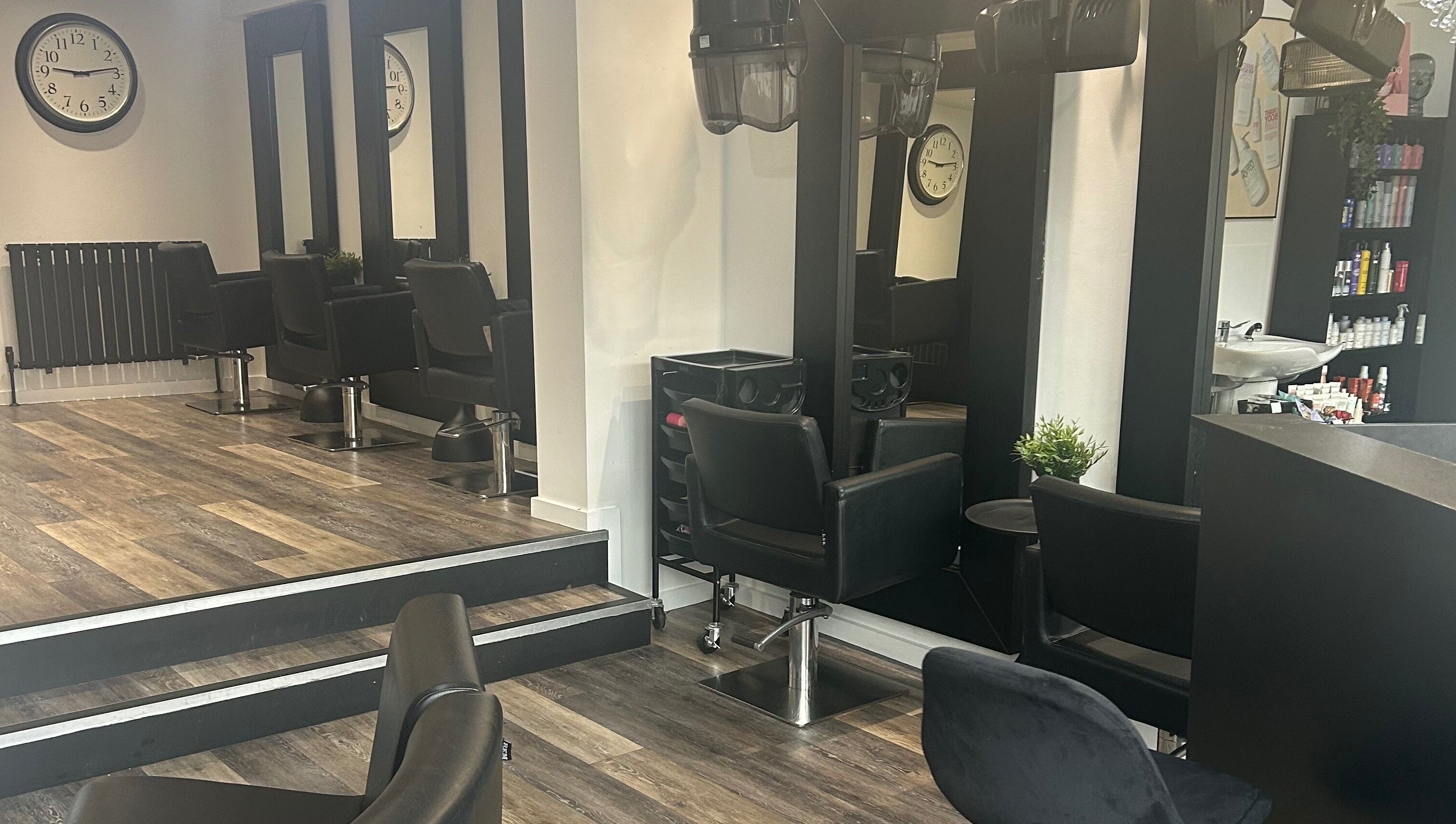 Modern salon setup at Hair and Beauty Gallery in Blackburn, England, GB with sleek black chairs and large mirrors.