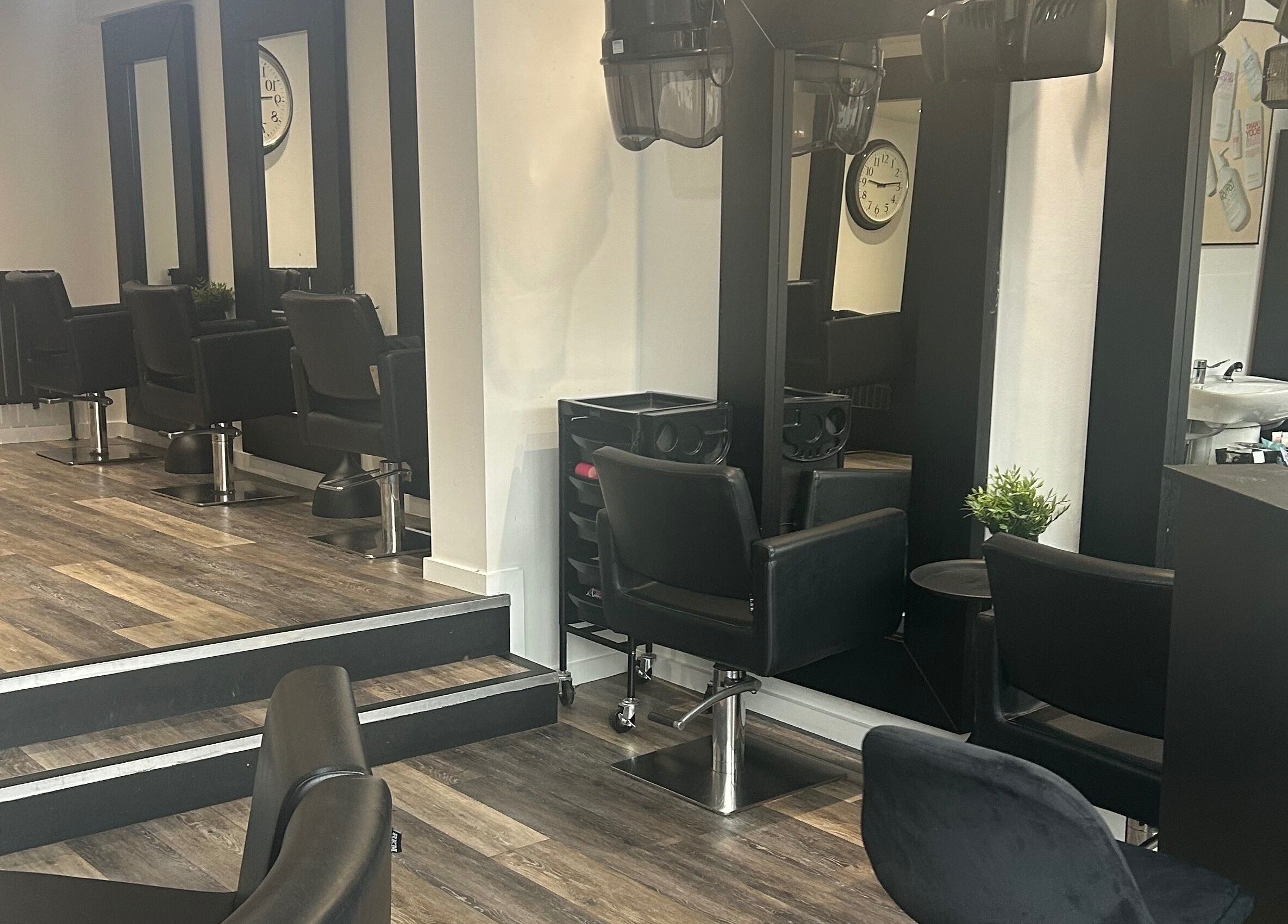 Modern salon setup at Hair and Beauty Gallery in Blackburn, England, GB with sleek black chairs and large mirrors.