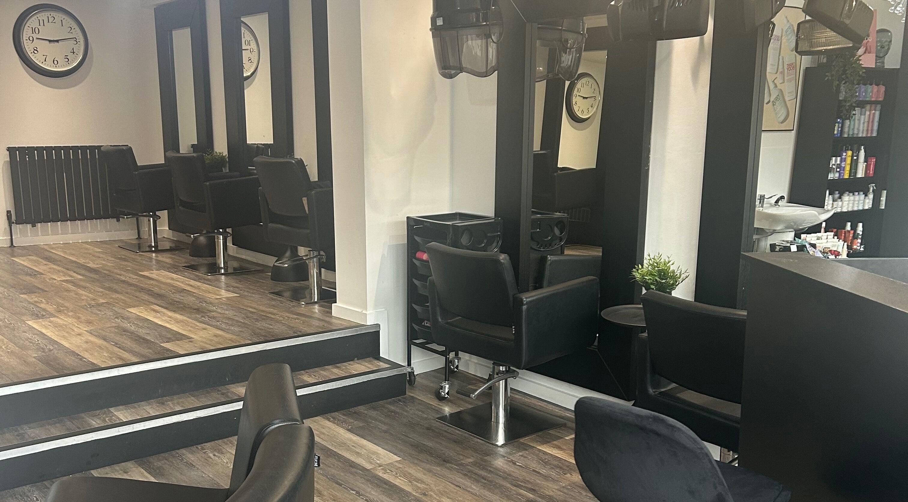 Modern salon setup at Hair and Beauty Gallery in Blackburn, England, GB with sleek black chairs and large mirrors.