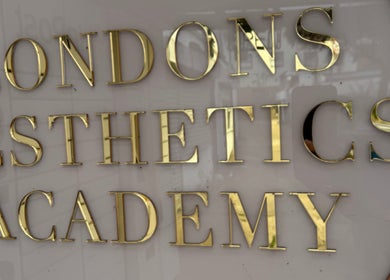 Close-up of 'London Aesthetics Academy' sign in gold letters at Levi Kimberley Aesthetics, West Drayton, England, GB.