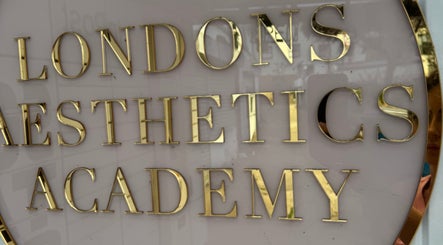 Close-up of 'London Aesthetics Academy' sign in gold letters at Levi Kimberley Aesthetics, West Drayton, England, GB.