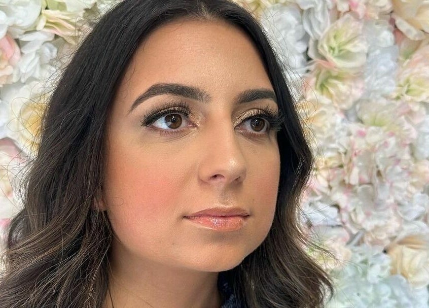 Woman with styled eyebrows at Lena Brows and Beauty Bar, Sandusky, Ohio, US, against a floral backdrop.