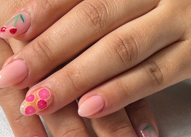 Vibrant fruit-themed nail art at Naya Saloon, Sanabis, Muḥāfaẓat Al-ʿāṣimah, BH, showcasing cherry and citrus designs.