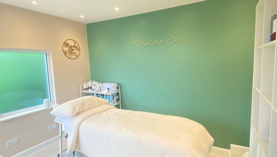 Peaceful treatment room at Bespoke Skin, Hoddesdon, England, GB with soothing green walls and a treatment bed.