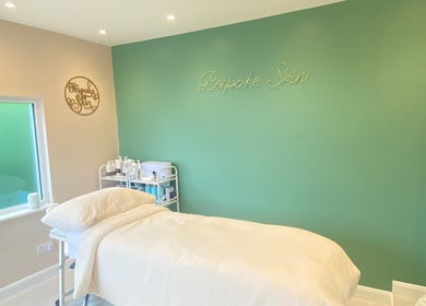 Peaceful treatment room at Bespoke Skin, Hoddesdon, England, GB with soothing green walls and a treatment bed.