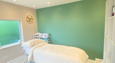 Peaceful treatment room at Bespoke Skin, Hoddesdon, England, GB with soothing green walls and a treatment bed.