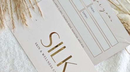 Elegant gift card from Silk Skin & Wellness Clinic in Hoveton, England, with golden accents on a white towel.