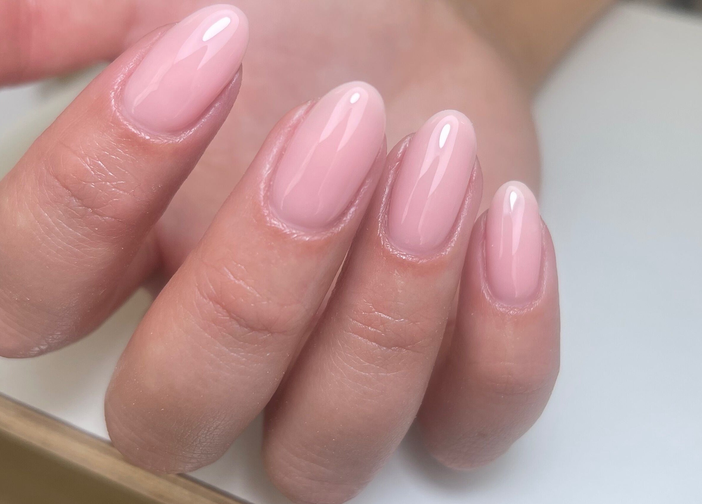 Elegant manicure at By Demi, Belfast, Northern Ireland, GB highlighting glossy pink almond-shaped nails.