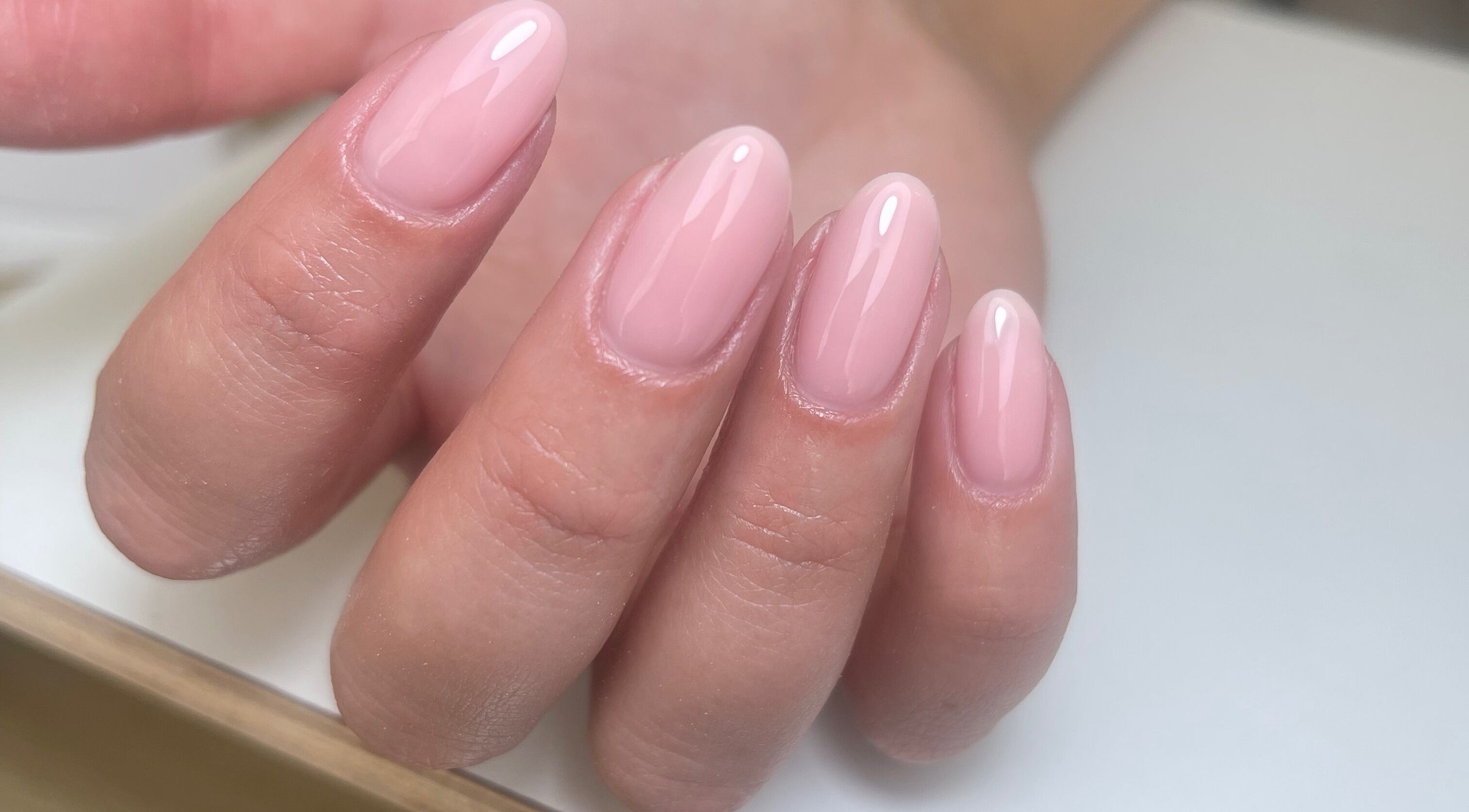 Elegant manicure at By Demi, Belfast, Northern Ireland, GB highlighting glossy pink almond-shaped nails.