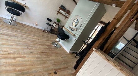 Modern salon interior at The Hair Studio, Sudbury, England, GB, featuring sleek chairs and rustic wooden floors.