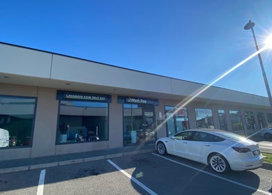 Vista esterna di WASH DOG 24h – DALMINE, situato a Dalmine, Lombardia, IT, con auto parcheggiate e cielo azzurro.