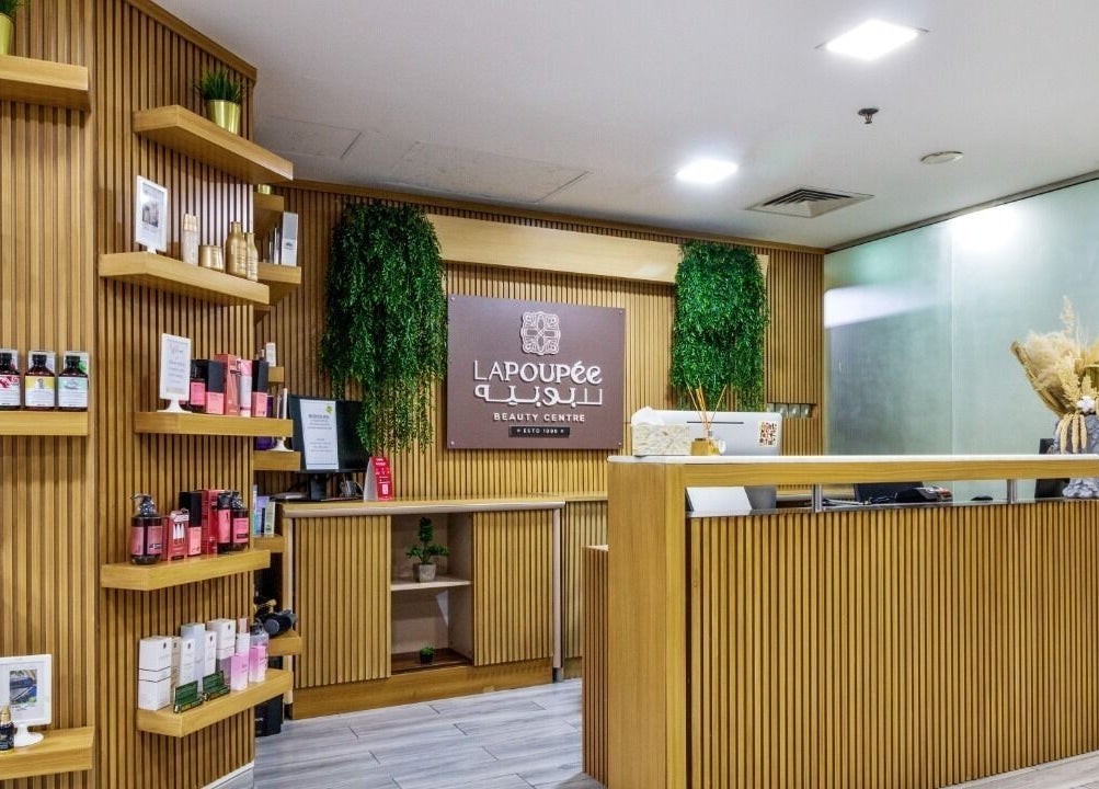 Modern reception area at La Poupee Home Service - Abu Dhabi, featuring wooden decor and beauty products.