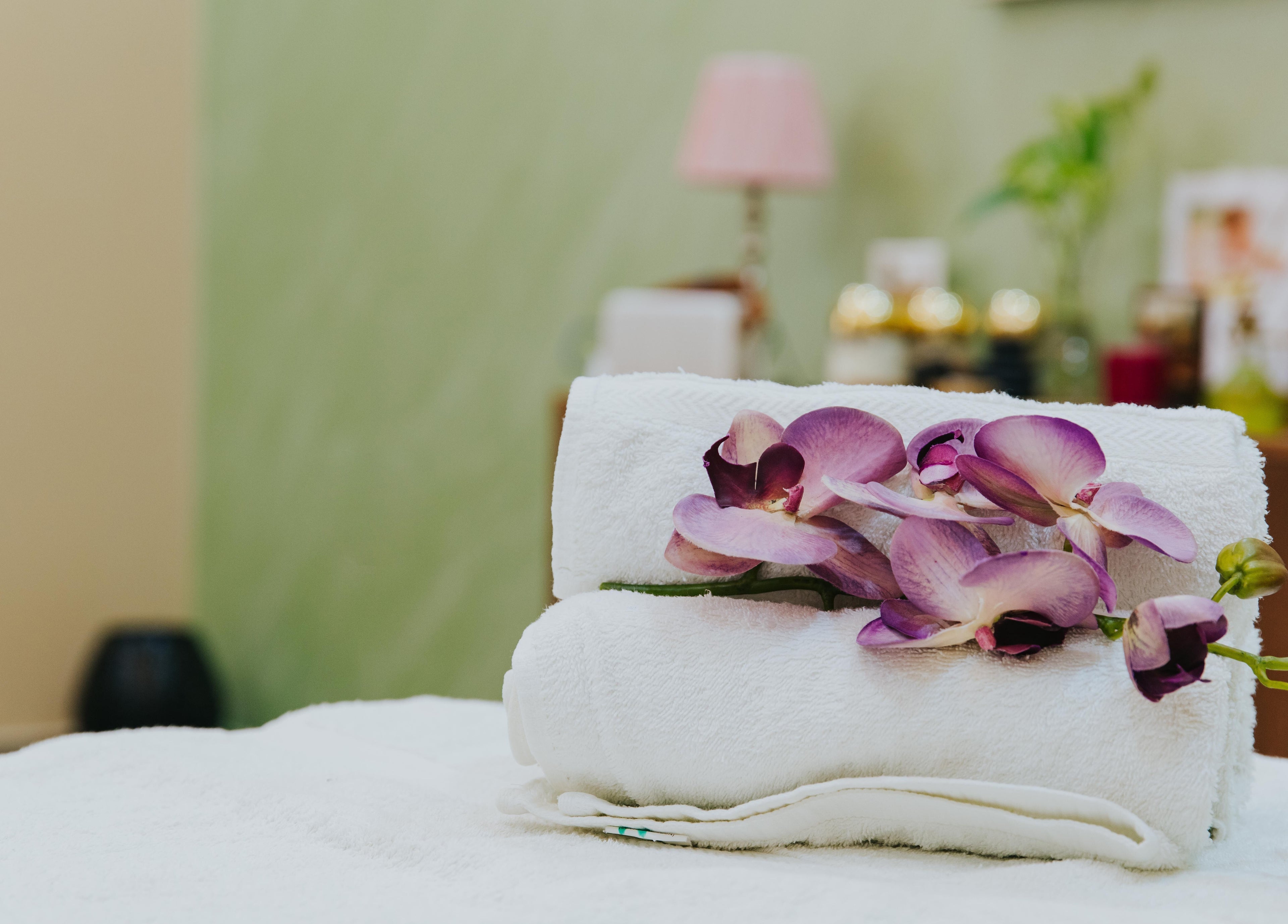 Elegant orchid on rolled towels at La Poupee Home Service - Al Ain, offering luxury in Al Ain, AE.