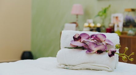 Elegant orchid on rolled towels at La Poupee Home Service - Al Ain, offering luxury in Al Ain, AE.