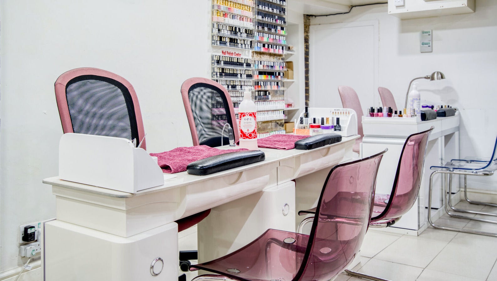 Elegant nail salon station at The Nail Lounge, London, England, GB, with sleek chairs and polishes on display.
