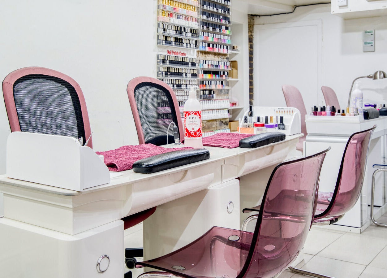 Elegant nail salon station at The Nail Lounge, London, England, GB, with sleek chairs and polishes on display.