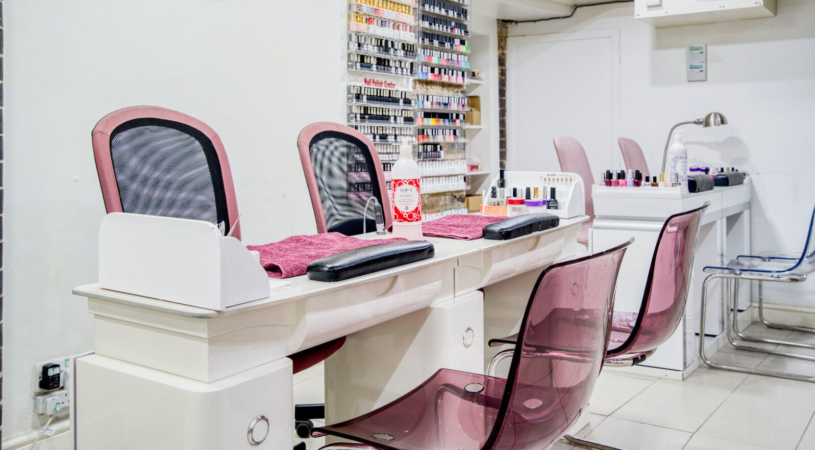 Elegant nail salon station at The Nail Lounge, London, England, GB, with sleek chairs and polishes on display.