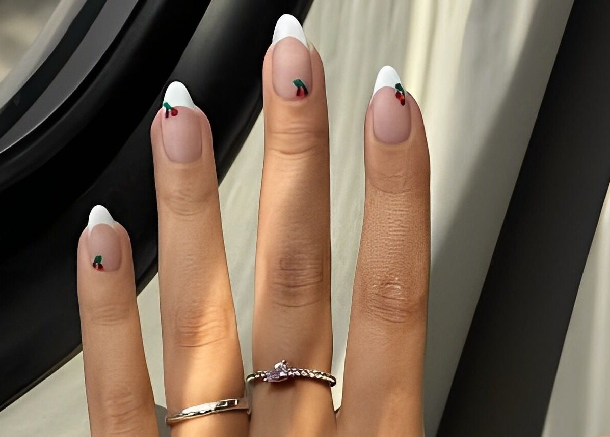 Stylish French manicure with cherry accents at The Nail Lounge, London, England, GB.