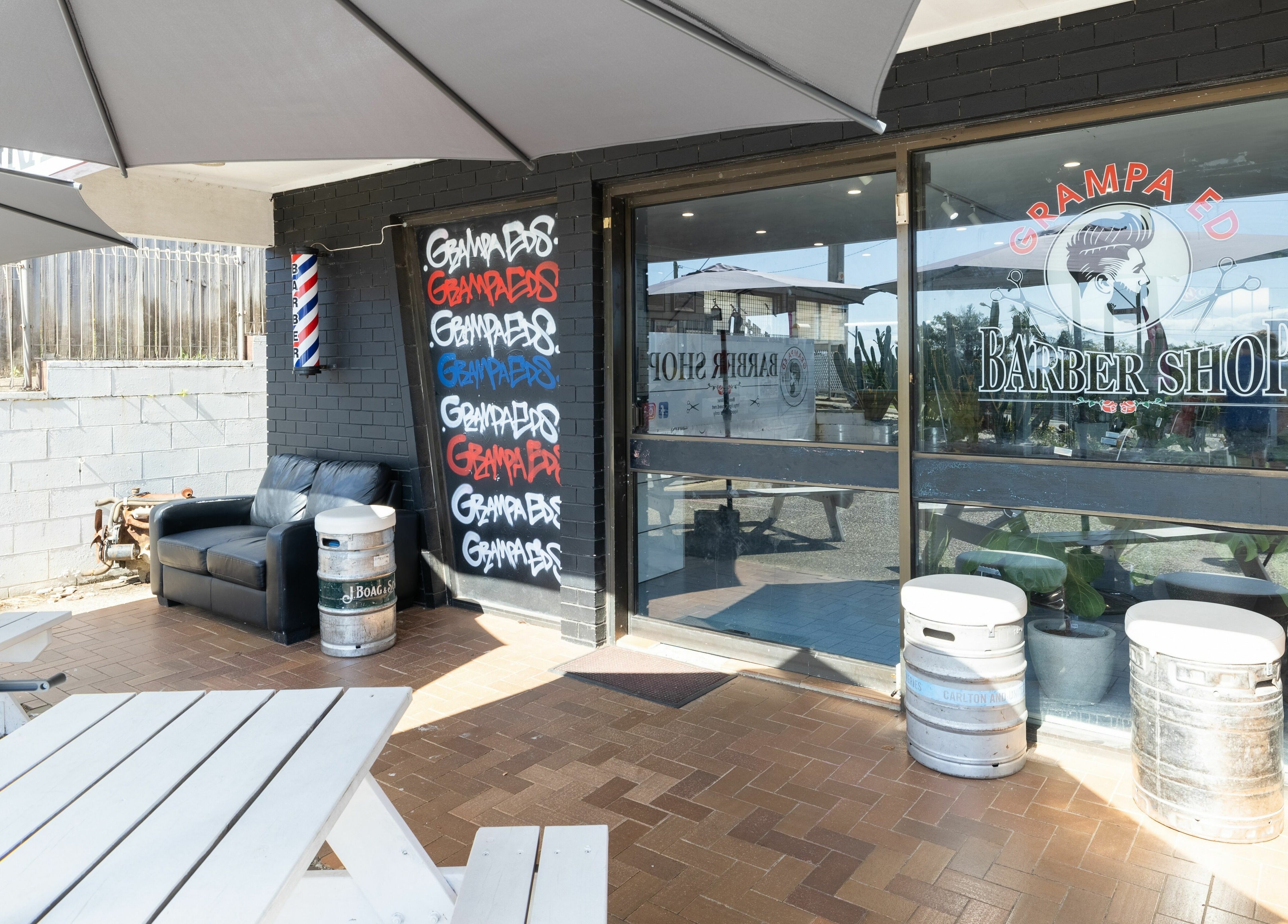 Entrance of Grampa Ed Barber Shop with outdoor seating in Banora Point, New South Wales, AU.