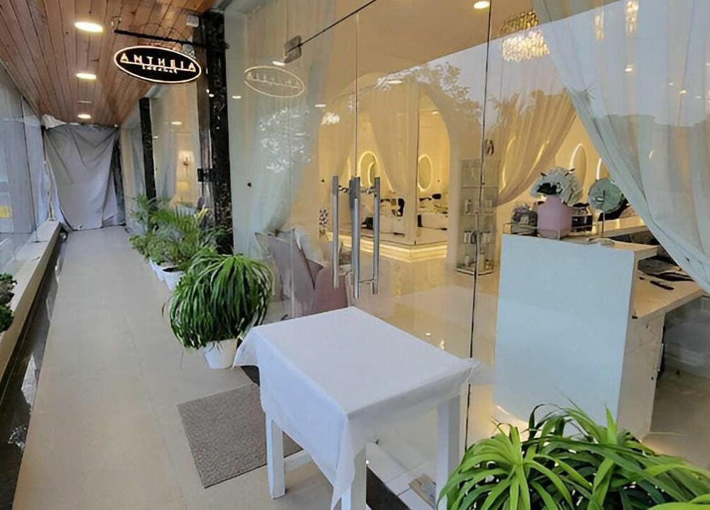 Glass entrance of Antheia Enhance in Dehradun, Uttarakhand, displaying elegant decor and lush greenery.