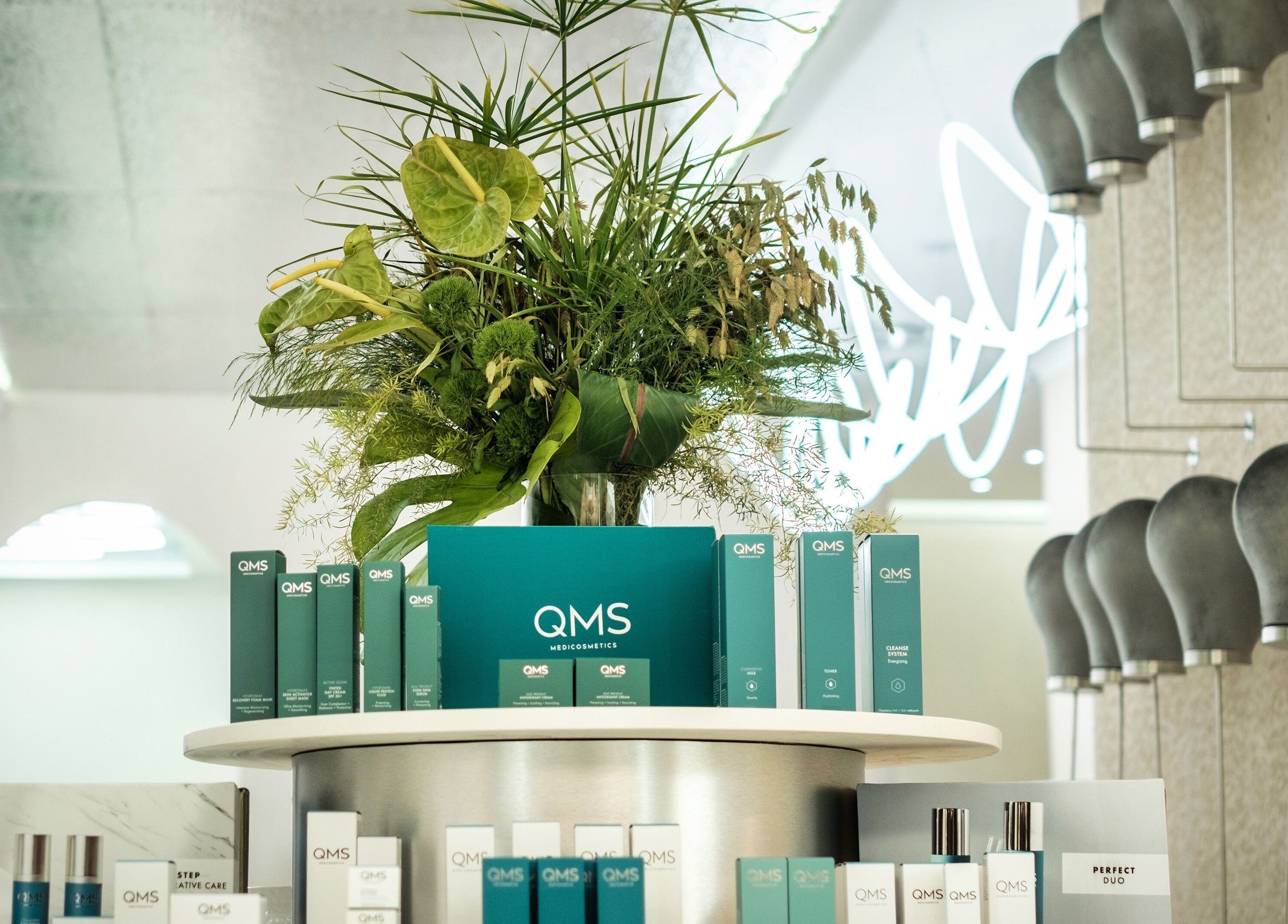 QMS cosmetics elegantly displayed at Society 1840, Johannesburg, Gauteng, ZA, with lush green plants.