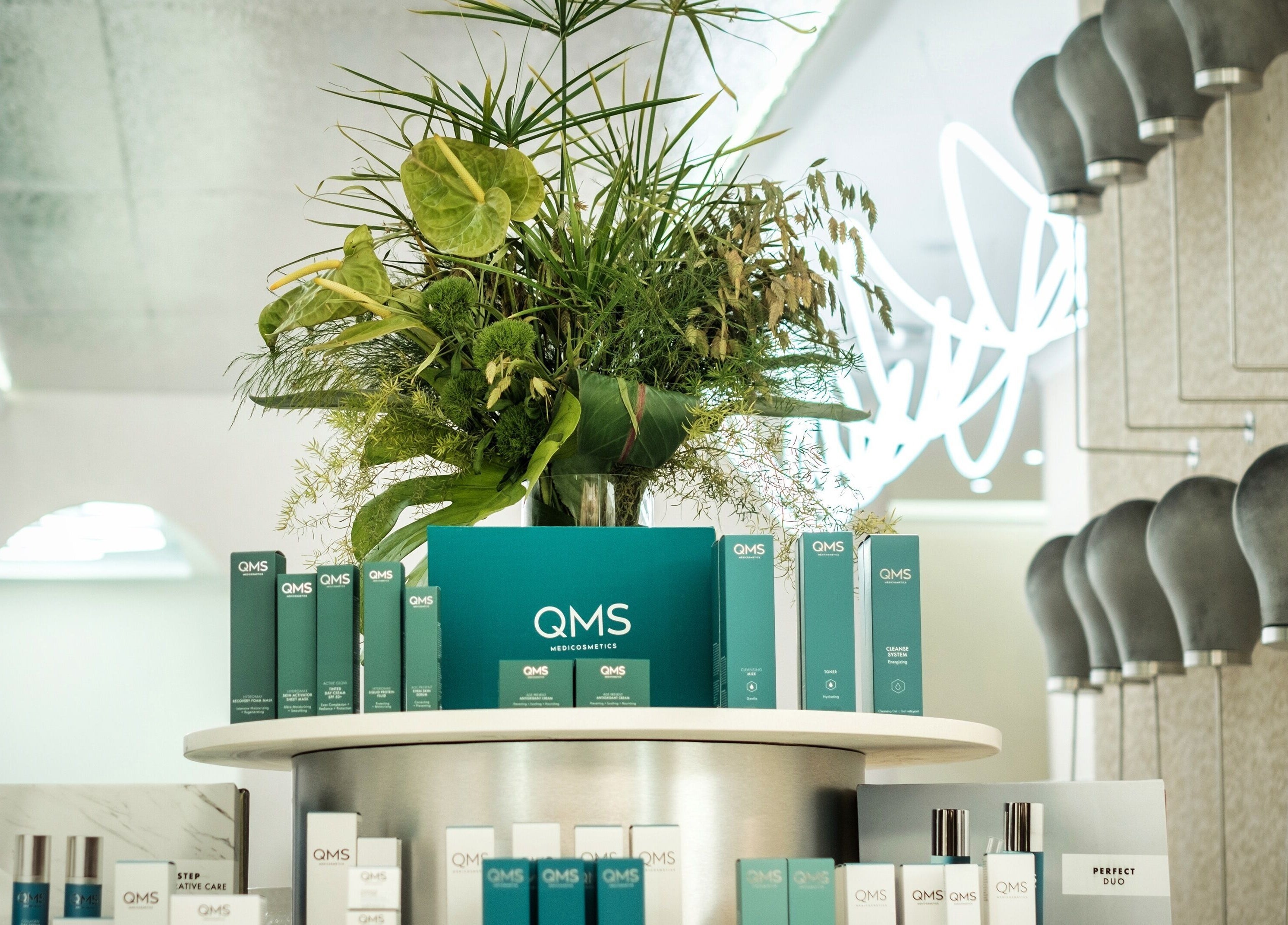 QMS cosmetics elegantly displayed at Society 1840, Johannesburg, Gauteng, ZA, with lush green plants.