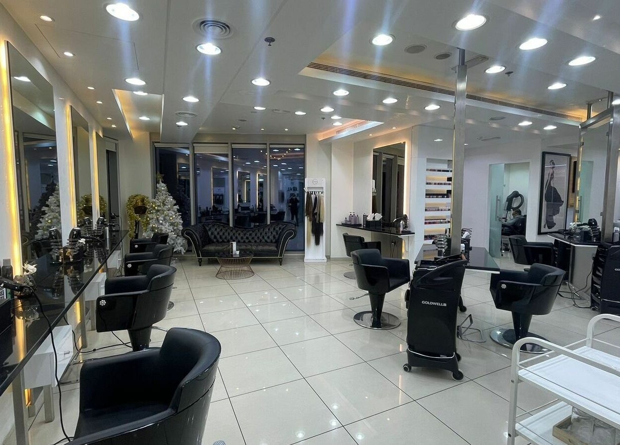 Elegant and modern interior of Karim and Amin Salon in Dubai, Dubai, AE featuring sleek black chairs and bright lighting.