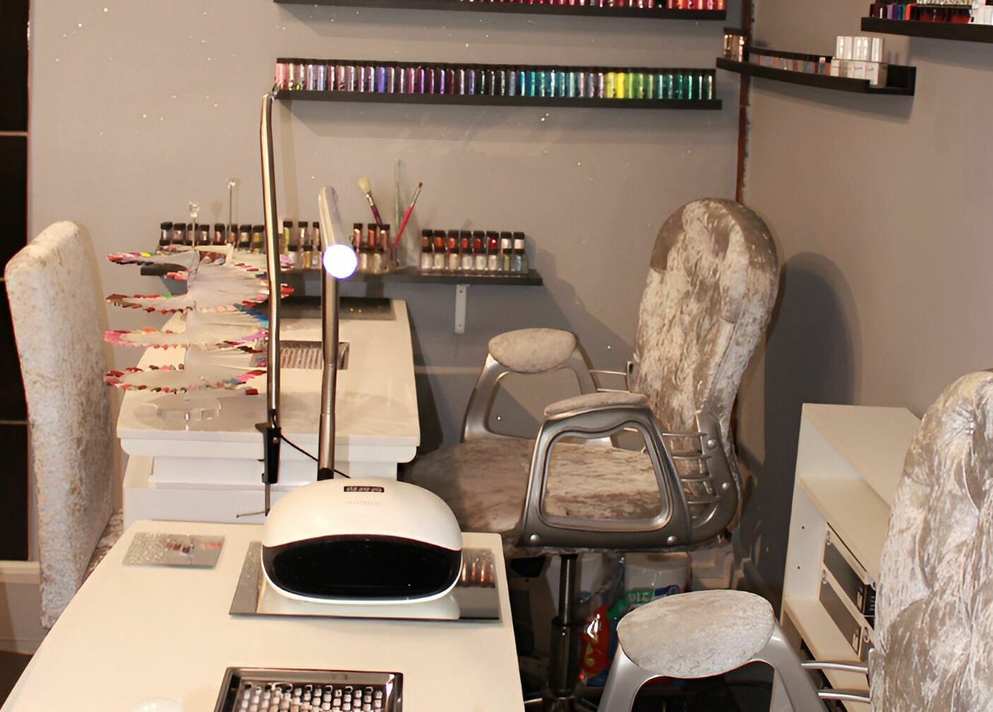 Nail salon setup at KM Hair and Beauty, Braintree, England, GB with plush chairs and nail polish display.