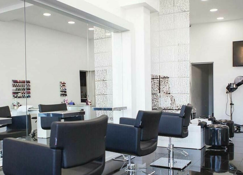 Modern salon interior at Maxx Mira Clinic, Enfield, England, GB with sleek black chairs and large mirrors.