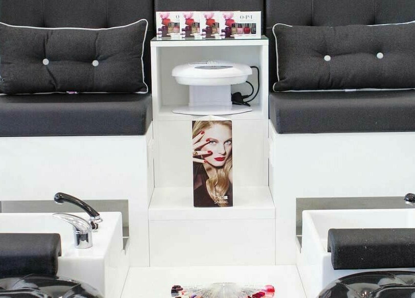 Elegant pedicure station at Maxx Mira Clinic, Enfield, England, GB, showcasing sleek black seating and nail polish display.