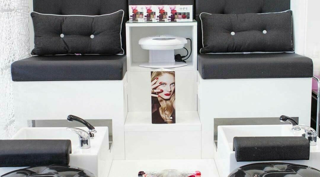 Elegant pedicure station at Maxx Mira Clinic, Enfield, England, GB, showcasing sleek black seating and nail polish display.