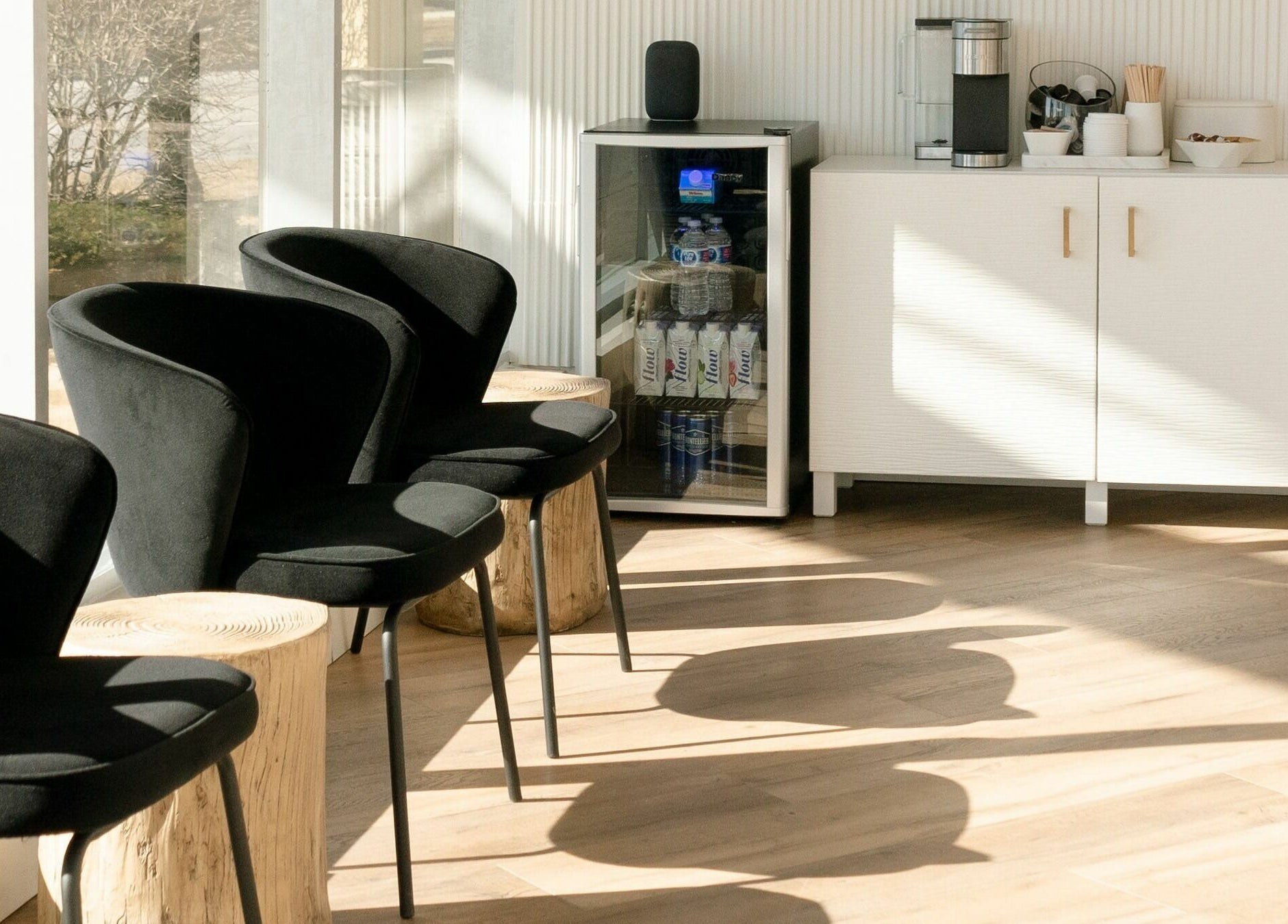 Modern waiting area at Laser Bar, Barrie, Ontario, CA, with black chairs and a stocked beverage station.