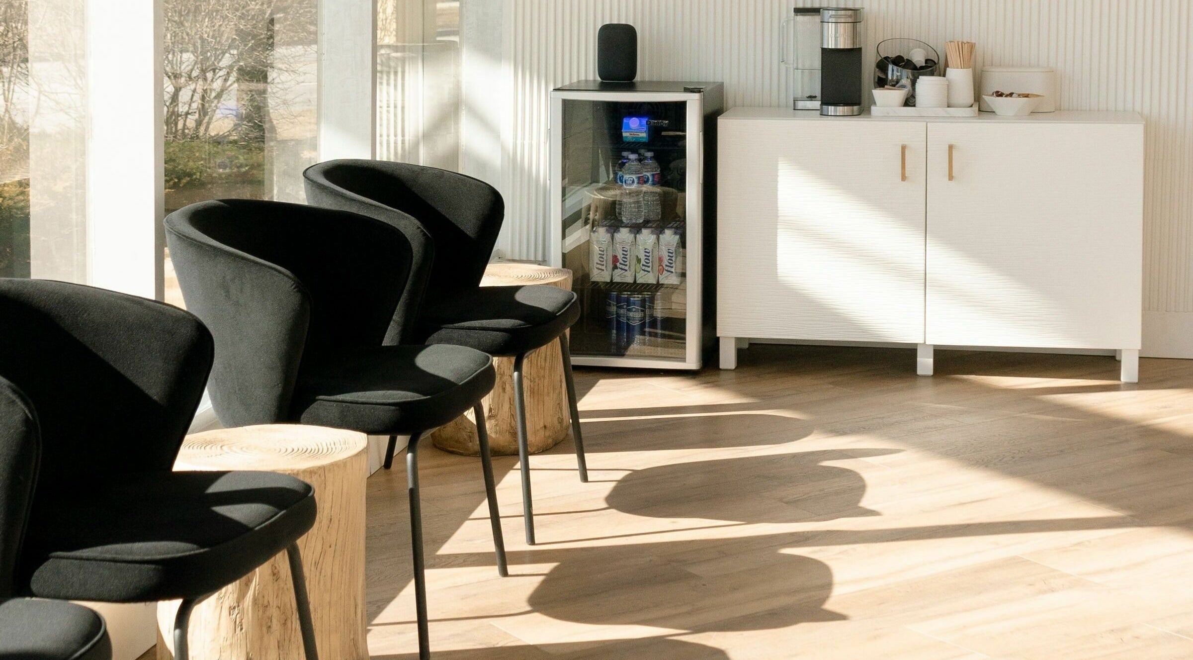 Modern waiting area at Laser Bar, Barrie, Ontario, CA, with black chairs and a stocked beverage station.