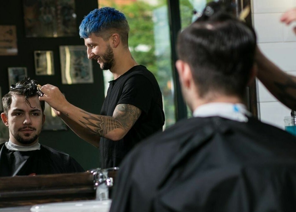 Frizer la Barber Society, Cluj-Napoca, Județul Cluj, RO, tundând un client cu profesionalism.