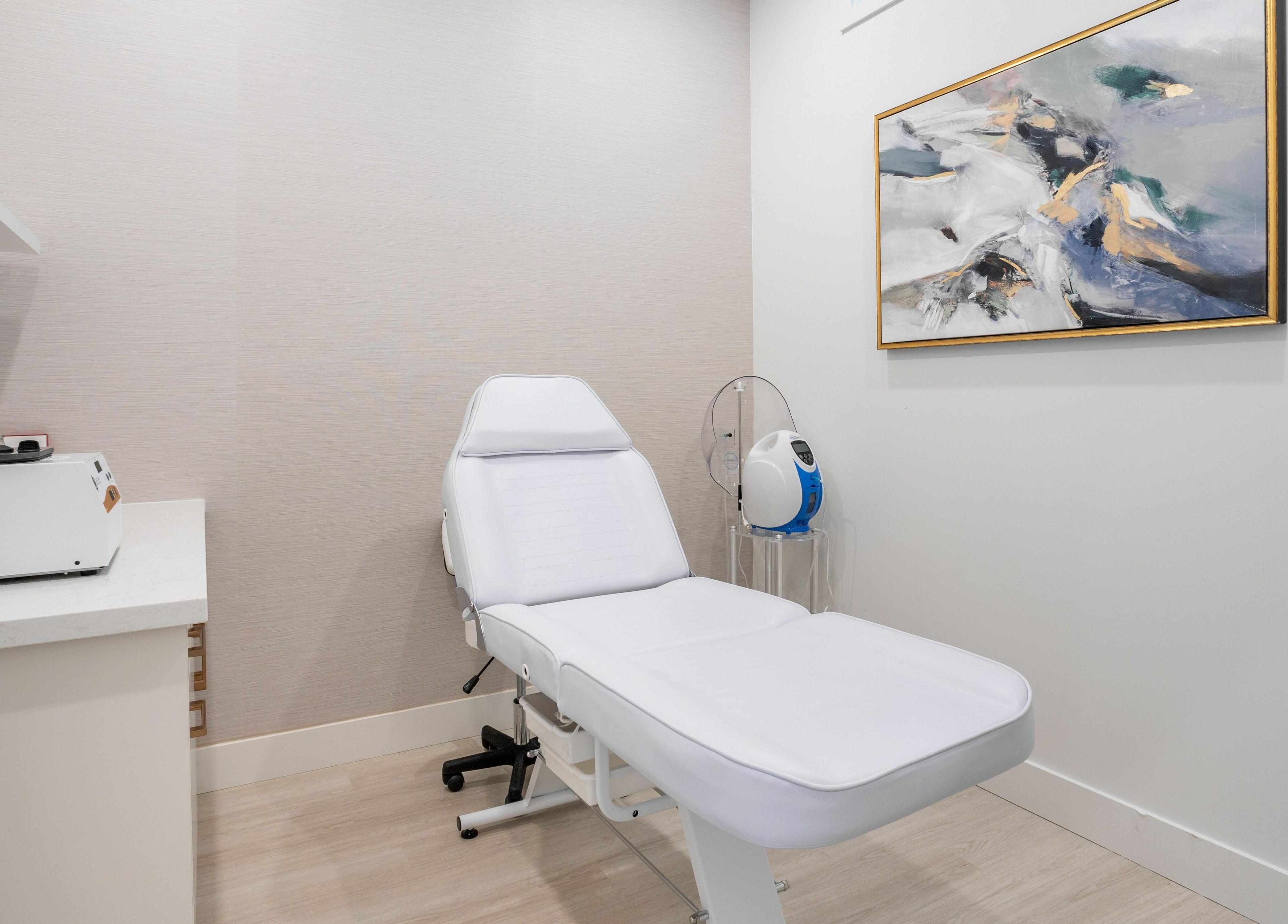 Modern treatment room at MG Aesthetics, Vaughan, Ontario, CA featuring a sleek white chair and abstract art.