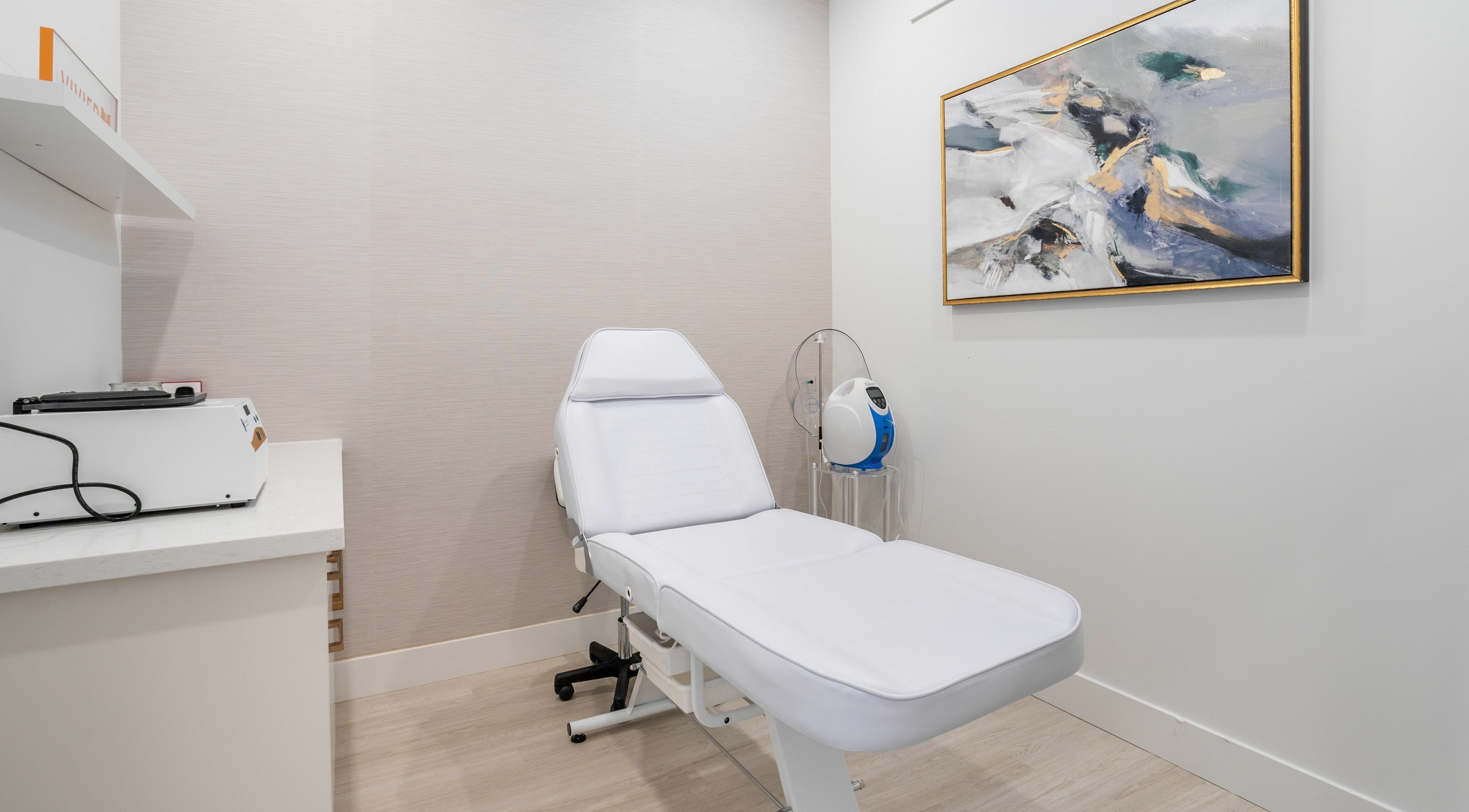 Modern treatment room at MG Aesthetics, Vaughan, Ontario, CA featuring a sleek white chair and abstract art.